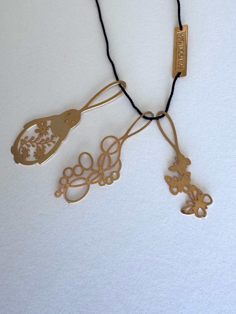 Very Rare. Artecnica gold toned 3 charm pendant necklace on black cord.